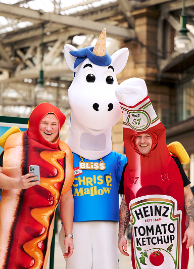 Hotdog mascots on either side of a unicorn mascot
