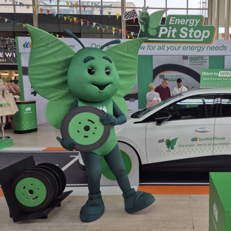 Mascot for Scottish Power standing next to car with a toy wheel in his hands