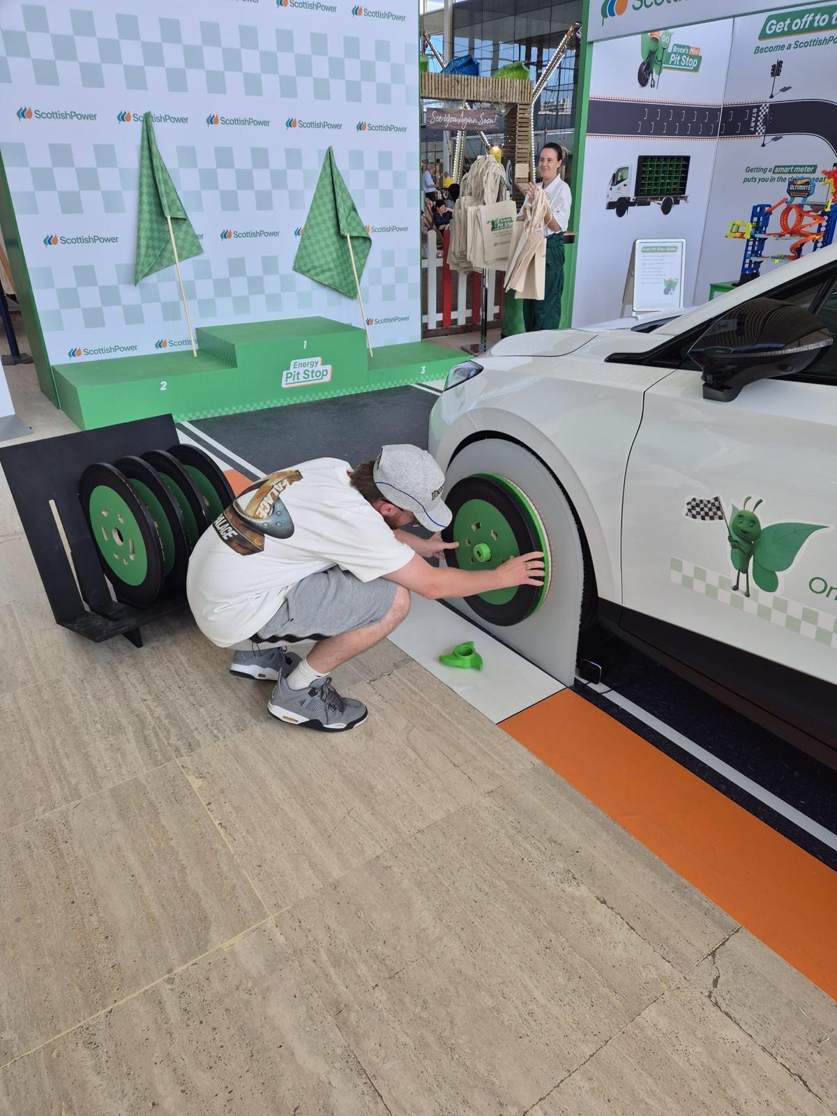 Man placing wheel disk onto car as part of game
